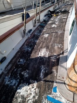 Entre la desgastada cubierta del barco, con pintura descascarada y manchas de óxido, cuerdas y herramientas insinúan historias de aventuras marítimas, rindiendo homenaje a la experiencia de Grandval Náutico en mantenimiento de barcos en Barcelona.
