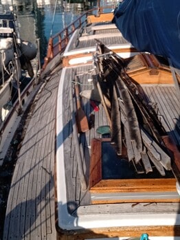 La cubierta de un barco atracado, con tablones de madera y el equipo cuidadosamente ordenado, reposa tranquilamente sobre el agua. Perfectamente situado para los entusiastas de Grandval Náutico o aquellos interesados en el mantenimiento de barcos en Barcelona.