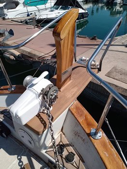 La proa del barco, que muestra un púlpito de madera y una cadena robusta, presenta un mecanismo de cabrestante cuidadosamente mantenido. Está elegantemente atracado en el puerto deportivo, encarnando el espíritu de Grandval náutico y reflejando el experto mantenimiento de barcos en Barcelona.