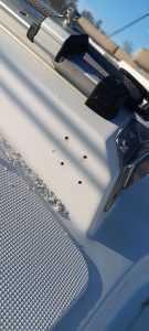 Primer plano de la cubierta de un barco en Grandval Náutico, que revela un accesorio de metal y múltiples pequeños agujeros perforados en la superficie blanca, lo que indica un meticuloso mantenimiento de barcos en Barcelona.