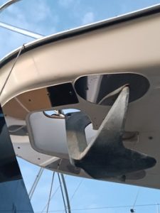El ancla, en su posición de almacenamiento debajo del casco, reflejaba el cielo azul claro, un testimonio del meticuloso mantenimiento de barcos en Barcelona.