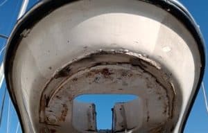 La vista inferior del casco de un barco, que muestra signos de desgaste y óxido contra un fondo de cielo azul, insinúa la necesidad de mantenimiento de barcos en Barcelona.