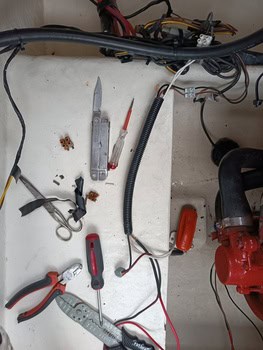 Un pequeño espacio de trabajo con herramientas que incluyen alicates, una multiherramienta, un destornillador, cables y conectores esparcidos sobre una superficie blanca insinúa un trabajo eléctrico o mecánico en curso, tal vez parte del mantenimiento de barcos en Barcelona en el famoso Grandval Náutico.