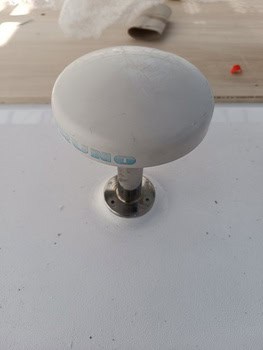 Una antena blanca, en forma de seta, que recuerda al estilo grandval náutico, está montada sobre una superficie plana con una base metálica.