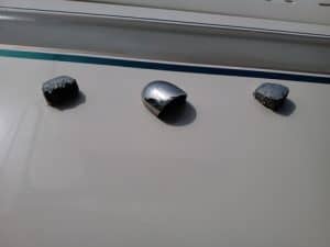 Primer plano de una superficie blanca con un aplique metálico central que recuerda al diseño náutico de Grandval, flanqueado por dos apliques exentos a cada lado.