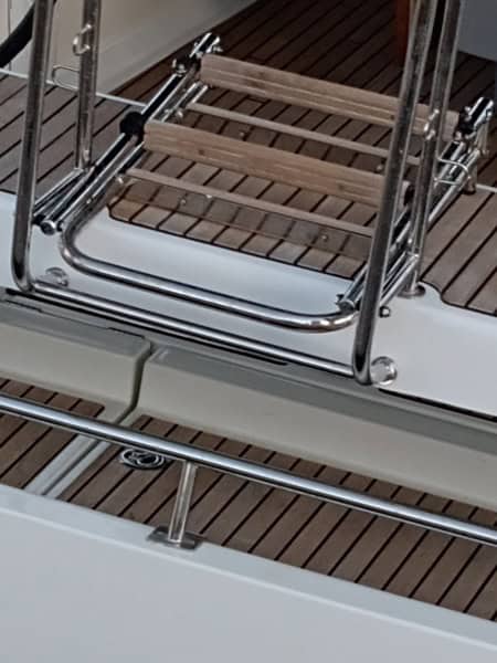 Una escalera de metal y madera en un barco con cubierta de madera, ideal para aquellos que buscan la calidad artesanal que encontrarán en Grandval Náutico.