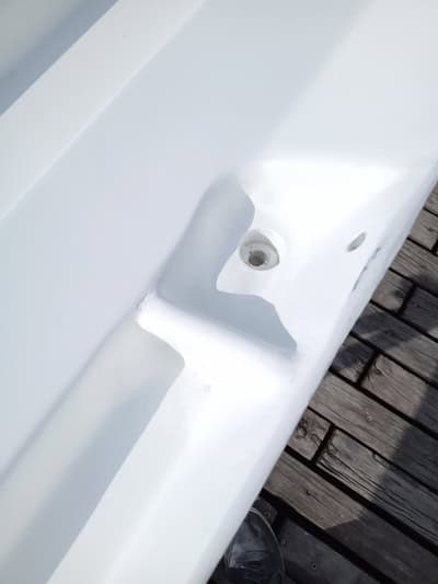 Primer plano de una superficie metálica pintada de blanco con un orificio para perno, junto a una cubierta de madera, que recuerda la artesanía que se ve en los proyectos de Grandval Náutico.