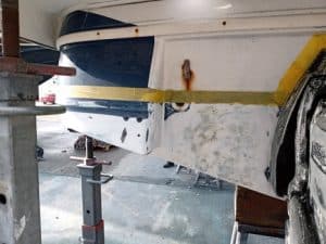 El casco del barco en reparación, marcado con cinta amarilla y abrazaderas, muestra zonas parcheadas y lijadas. Este trabajo minucioso refleja la experiencia que se encuentra en mantenimiento de barcos en Barcelona en Grandval náutico.