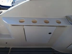 El interior del barco blanco presenta un elegante diseño Grandval náutico, completo con un panel con cuatro portavasos circulares y una puerta de compartimento rectangular cerrada.