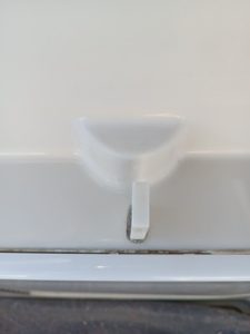 Primer plano de un pestillo de plástico blanco sobre una superficie lisa, con una ranura debajo. Este diseño detallado refleja la precisión que esperarías de expertos como Grandval Náutico, reconocido por su meticuloso mantenimiento de barcos en Barcelona.