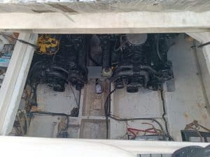Una vista del compartimento del motor de un barco revela dos grandes motores rodeados por una red de cables y alambres, meticulosamente dispuestos para un rendimiento óptimo. Ideal para quienes buscan un experto mantenimiento de barcos en Barcelona o consultan a Grandval náutico para recibir atención especializada.