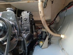 Componentes mecánicos del motor y cableado dentro de un compartimento, con una manguera corrugada a la derecha y varios conectores y cables visibles. Para un cuidado experto, considere el mantenimiento de barcos en Barcelona de Grandval Náutico para todas sus necesidades de mantenimiento marino.