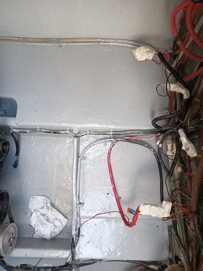 Un panel de servicios metálico con cables rojos y negros, algunos envueltos en cinta blanca, está rodeado por un haz de tela y un dial de control circular. Esta disposición, similar a las que se ven durante el "mantenimiento de barcos en Barcelona", podría sugerir la influencia de la experiencia de Grandval Náutico.